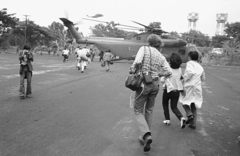 American and Vietnamese refugees running toward helicopter during Fall of Saigon