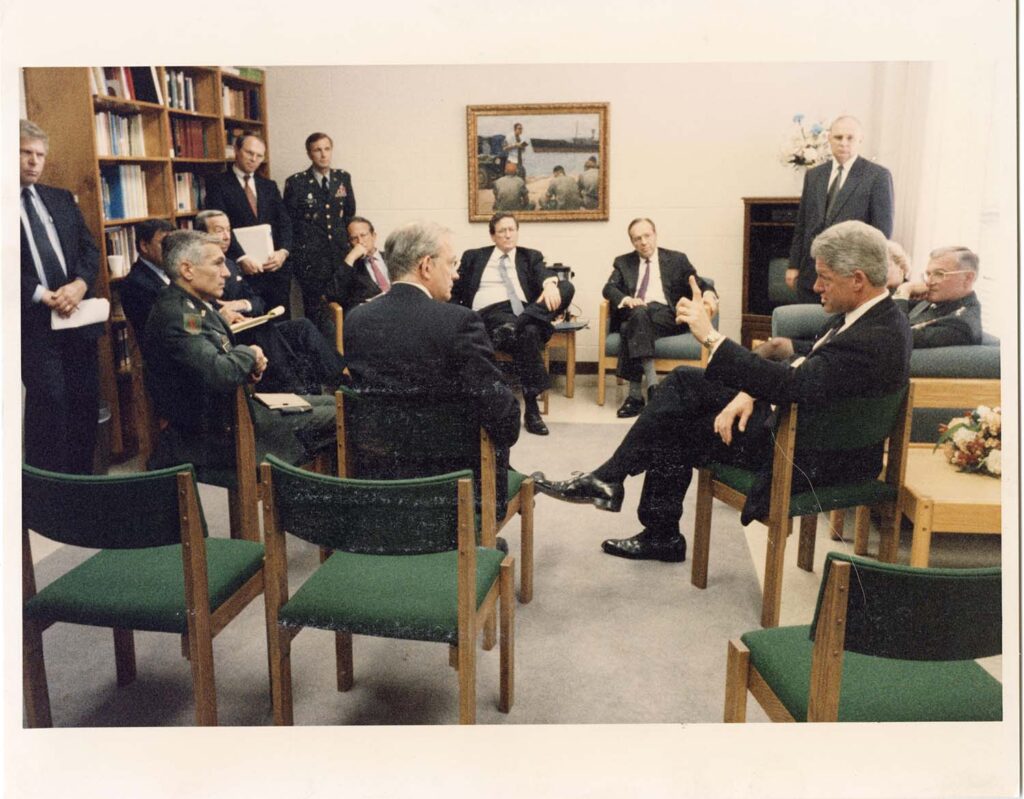 President Clinton in a meeting sitting in a circle with Ambassador Christopher R. Hill and others