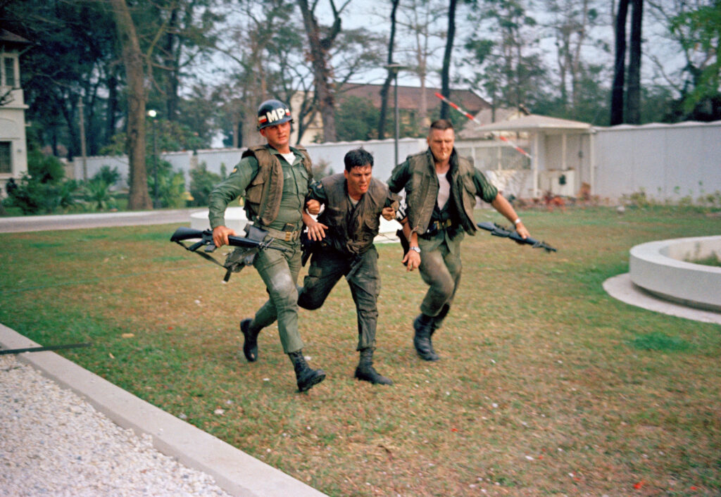 Two soldiers carry a man that is injured