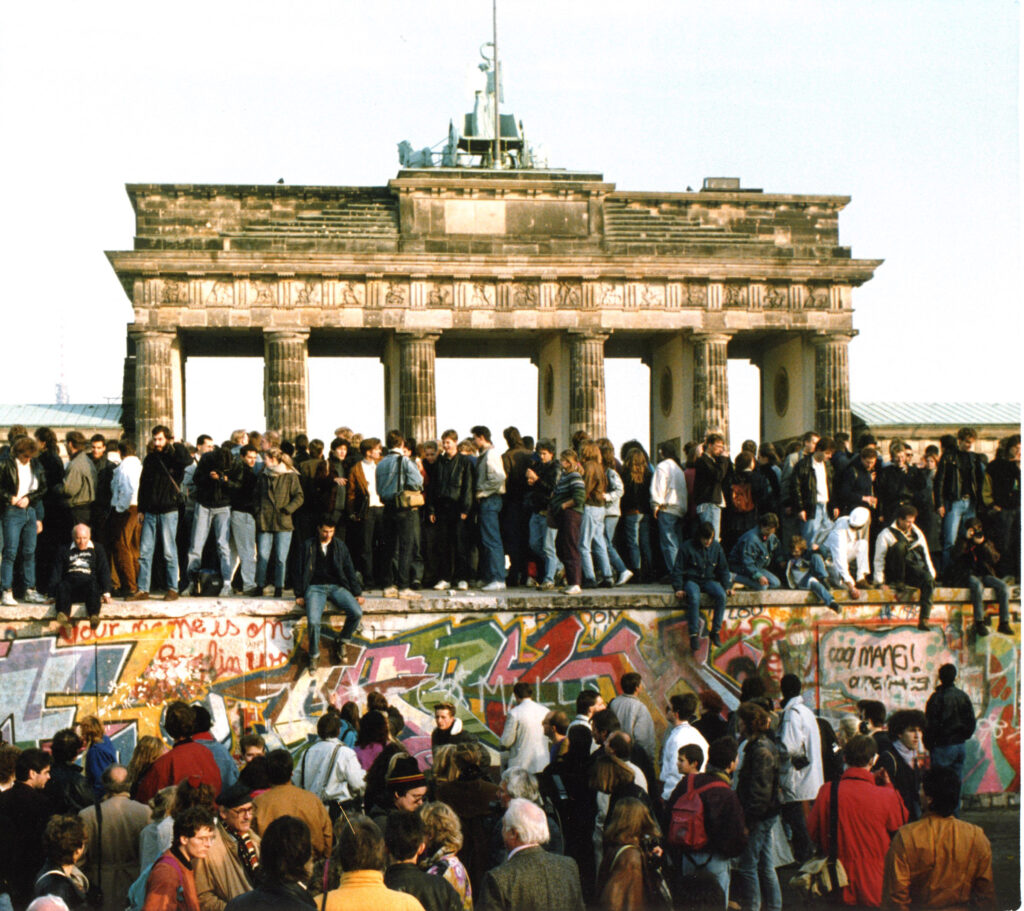 Un grupo de personas en la cima del Muro de Berlín mientras se desmorona