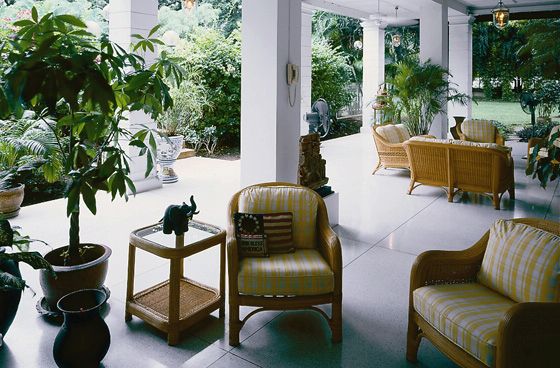 A marble veranda with wicker furniture overlooking a garden