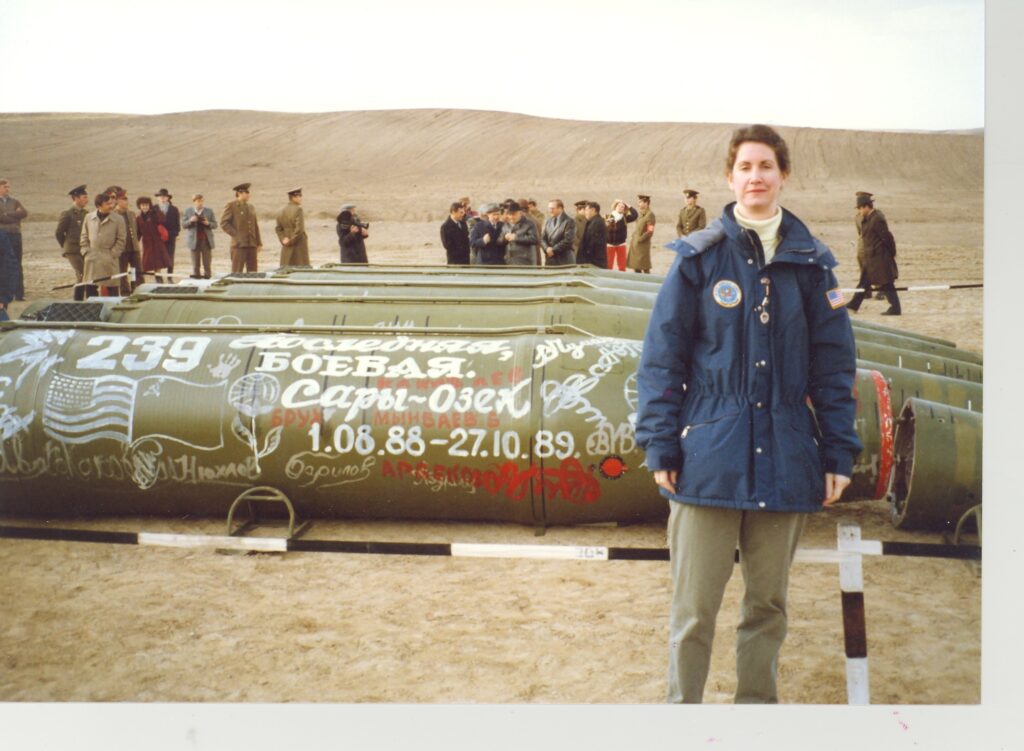 Photo of Eileen Malloy standing in front of missiles in Saryozek, Kazakhstan.
