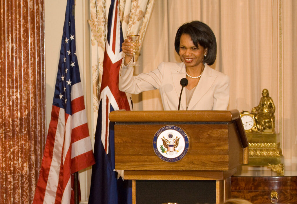 Secretary of State Condoleezza Rice raises a glass from the podium in honor of Australian Prime Minister John Howard, who can be seen sitting at lower left.