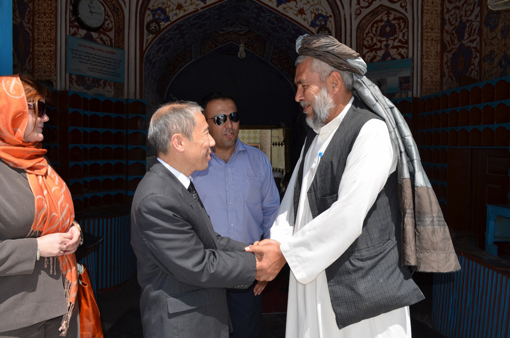 Yamamoto shakes hands with a religious leader outside a mosque in Afghanistan