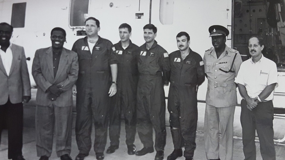 Gutierrez stands with U.S. Coast Guard members in front of a plane