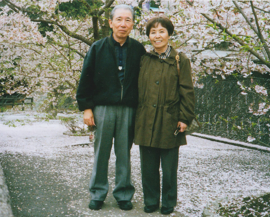 Ambassador Yamamoto's mother and father stand in front of cherry blossoms