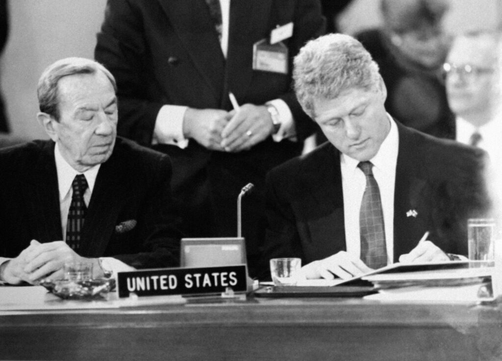 Warren Christopher and Bill Clinton signing a document