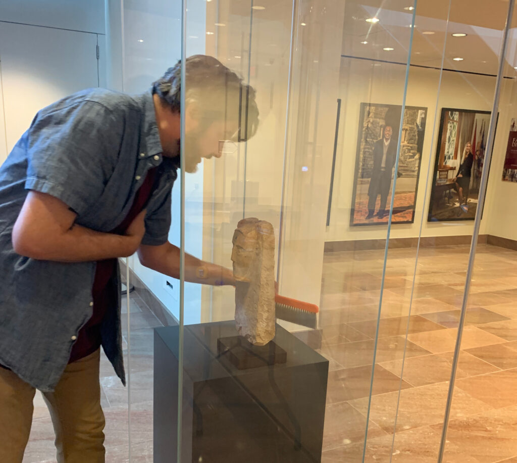A curator brushes the inside of the case for the monument