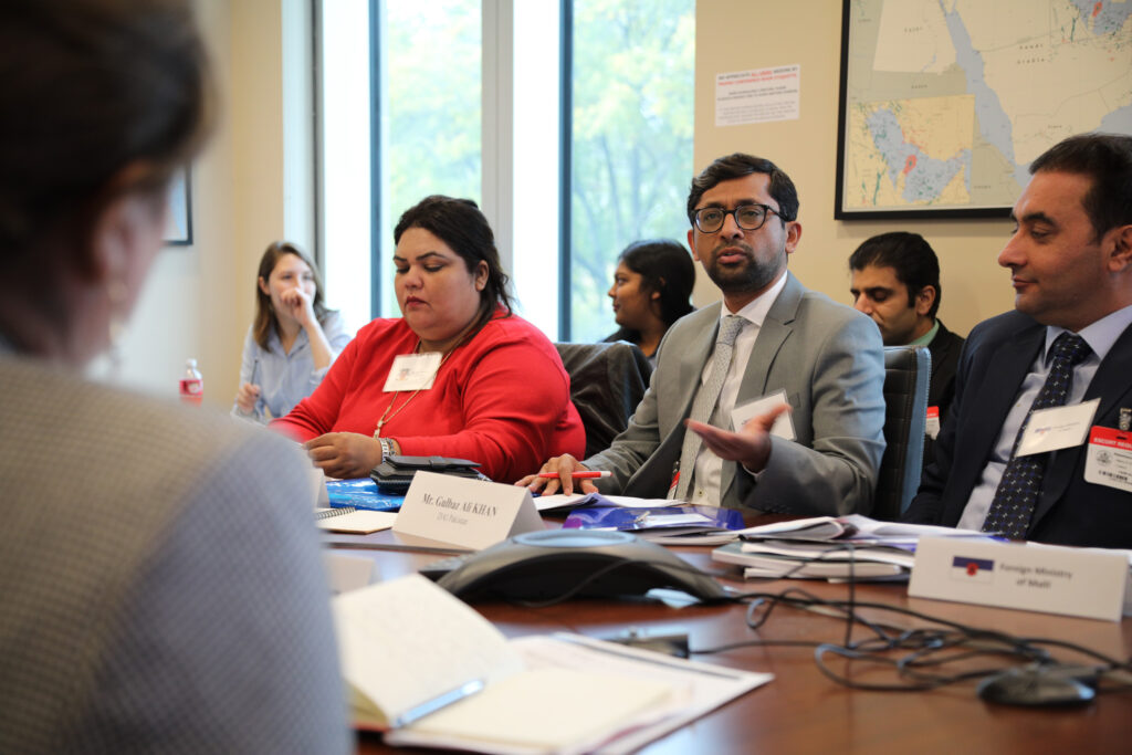 A group of professionals take part in a diplomacy simulation in a conference room