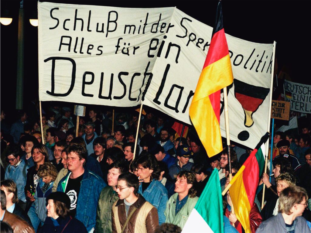 East German demonstrators hold a banner reading “One Germany” in a peaceful rally in Dresden, Germany.
