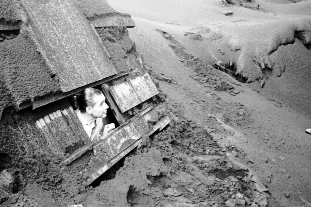 telles pokes head out of home's window covered in volcanic ash