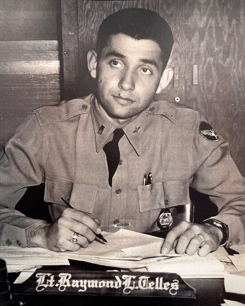 raymond telles sitting a desk in uniform