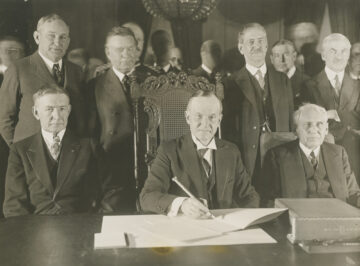 President Coolidge signing the Kellogg Briand Pact with the ceremonial pen.