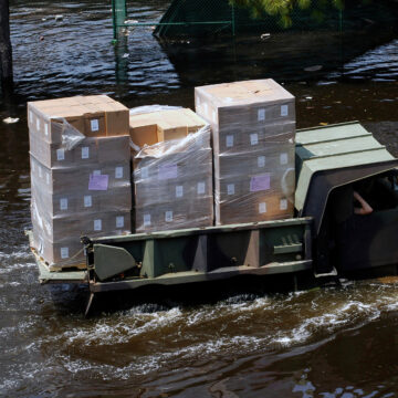 A truck carrying boxes of supplies through the water