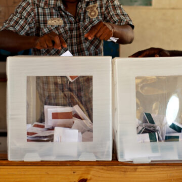 A person putting a vote into a ballet box