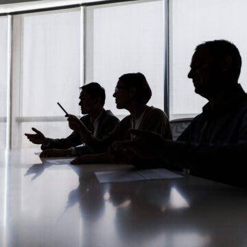 Silhouettes of three people in a conference room