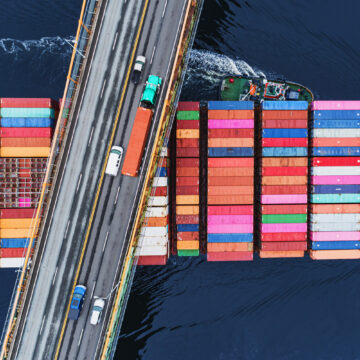 Aerial view of shipping containers under a bridge