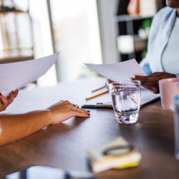 Person handing a paper to another person