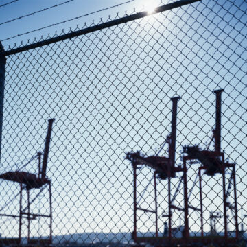 Cranes at a port behind a fence