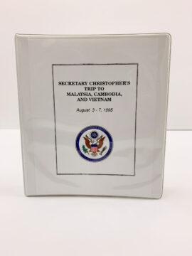 A white binder that says “Secretary Christopher's Trip to Malaysia, Cambodia, and Vietnam”
