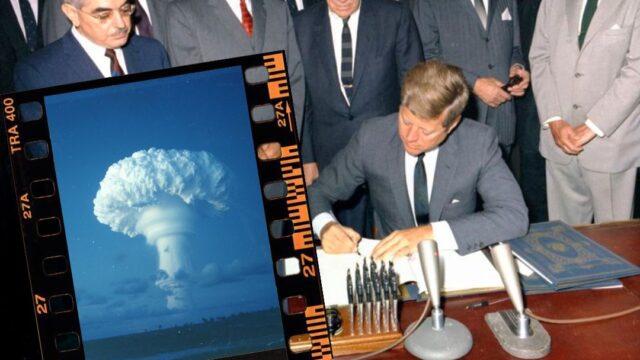 President JFK signing a treaty with a picture of a nuclear mushroom cloud super imposed