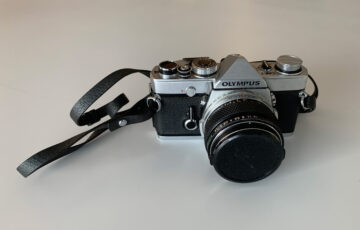 A film camera with lens and neck strap.
