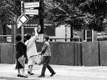 A West Berlin woman waves to people on the other side of the concrete wall dividing West and East Berlin.