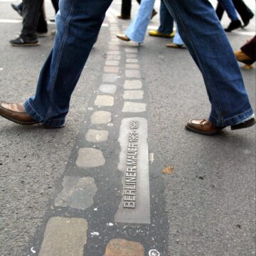 A passerby in Berlin crosses a memorial strip near the Brandenburg Gate where the Wall once stood.