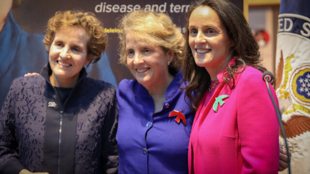 Alice Albright, Anne Albright, and Katie Albright stand in front of a portrait of their mother Madeleine Albright