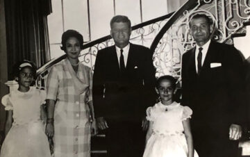 JFK standing with the telles family in front of a staircase