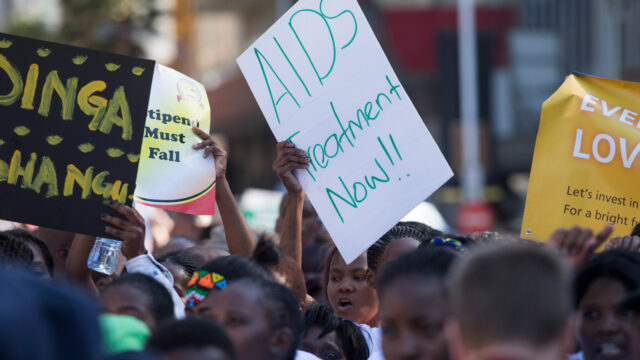 A woman holds up a sign that says 