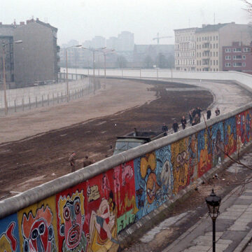 Foto: Luftaufnahme der Berliner Mauer mit Graffiti, im Hintergrund der Todesstreifen und Soldaten