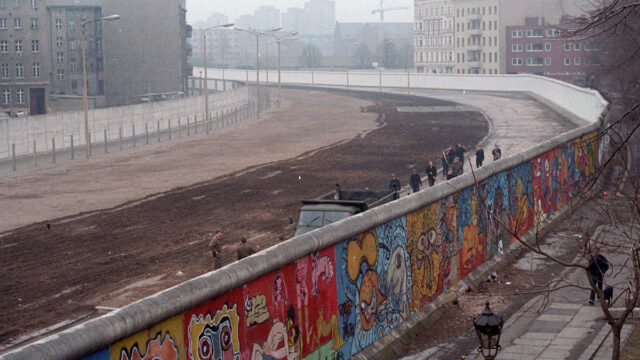 Foto: Luftaufnahme der Berliner Mauer mit Graffiti, im Hintergrund der Todesstreifen und Soldaten