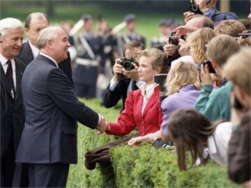 Foto: Michail Gorbatschow (neben ihm Richard von Weizsäcker) schüttelt einer jungen Frau im roten Jackett die Hand, neben ihr zahlreiche Fotografen