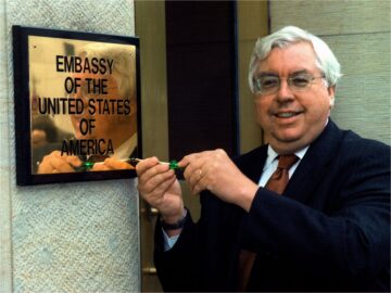US-Botschafter Kornblum schraubt Schild mit der Aufschrift „Embassy of the United States of America“ an eine Wand