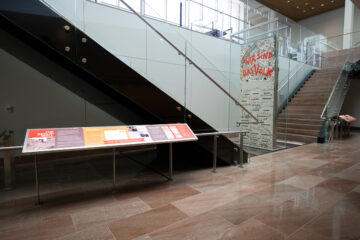 Foto: ein großes Mauerteil ist in einem Gebäude vor einer Treppe ausgestellt