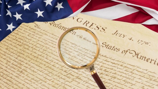 Magnifying glass over the declaration of indepedence with an american flag detail