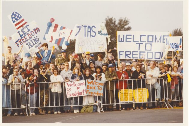 A crowd holds posters welcoming home the hostages