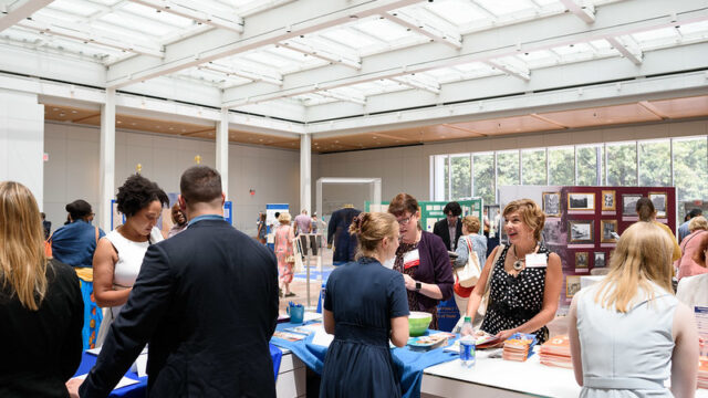 Participants in a teacher resource fair have a lighthearted discussion.