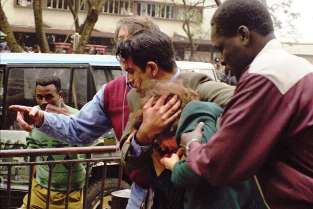 U.S. Commercial Officer Riz Khaliq shields Ambassador Bushnell as Foreign Service National George Mimba (right) and Foreign Service Officer Steve Nolan (left) assist in evacuating the ambassador from the site.