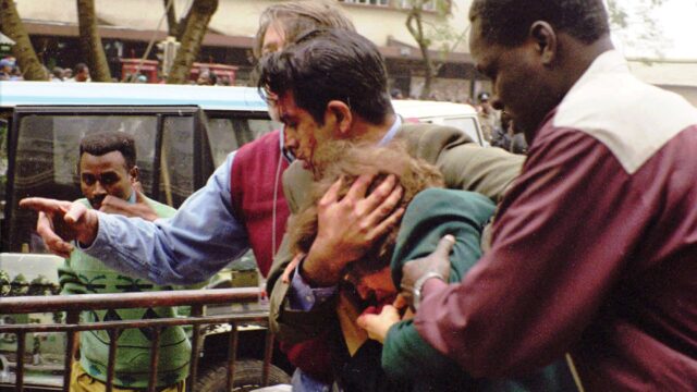 U.S. Commercial Officer Riz Khaliq shields Ambassador Bushnell as Foreign Service National George Mimba (right) and Foreign Service Officer Steve Nolan (left) assist in evacuating the ambassador from the site.