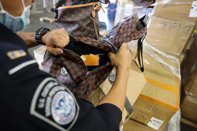 A bag being examined by a security officer with a badge.