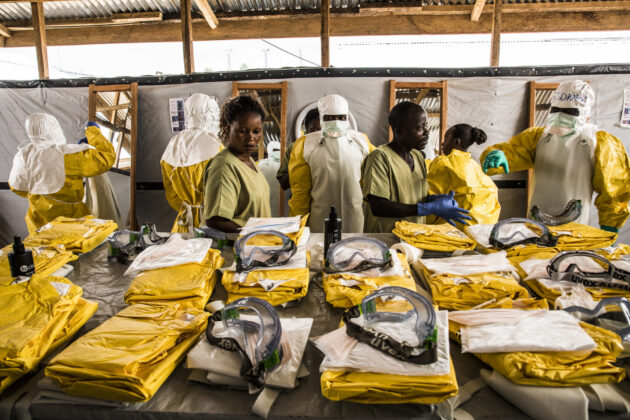 Photograph of responders wearing and preparing sets of protective equipment in response to an infectious disease outbreak.