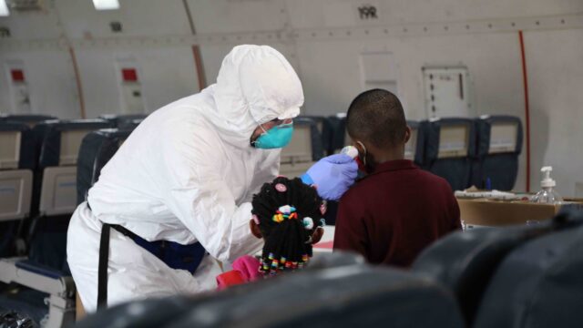 An Operational Medicine personnel takes the temperature of a passenger boarding in Cameroon