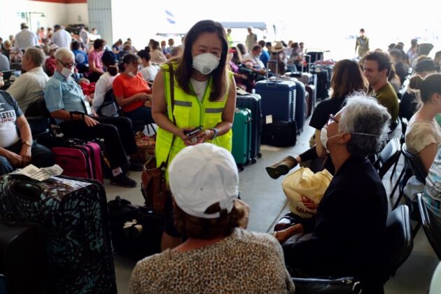 A woman speaks to an elderly couple in the airport in masks