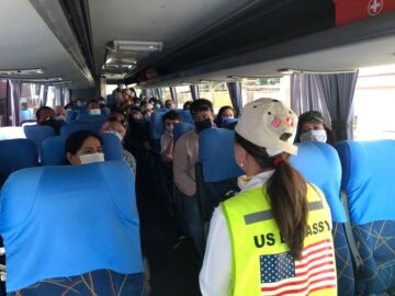 American passengers receive instructions from U.S. Embassy staff as they travel to the airport for their repatriation flights from Lima, Peru.