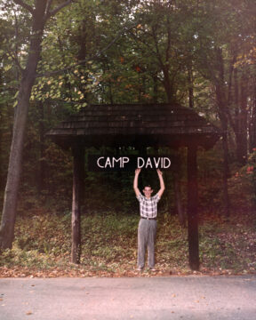 Boy points a sign above his head that says Camp David