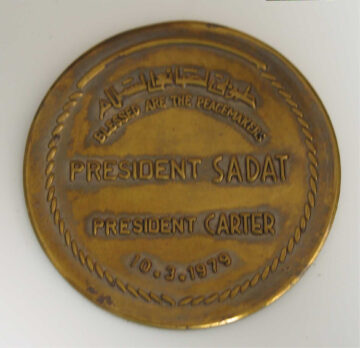 A gold coin that says President Sadat President Carter