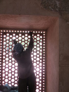A man in front of an Indian jali screen