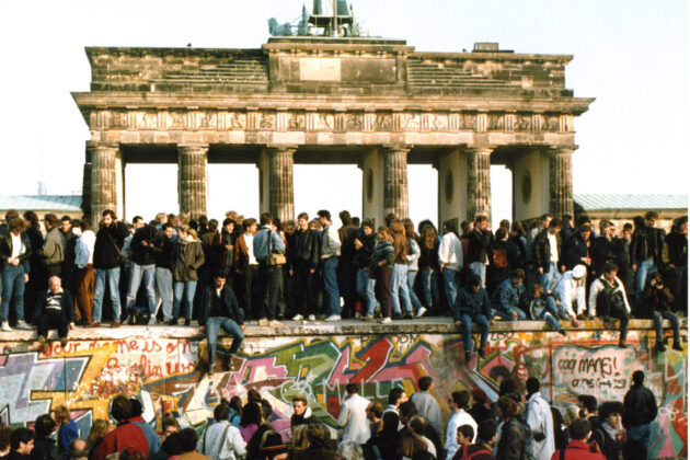 A group of people on top of the Berlin Wall as it comes down